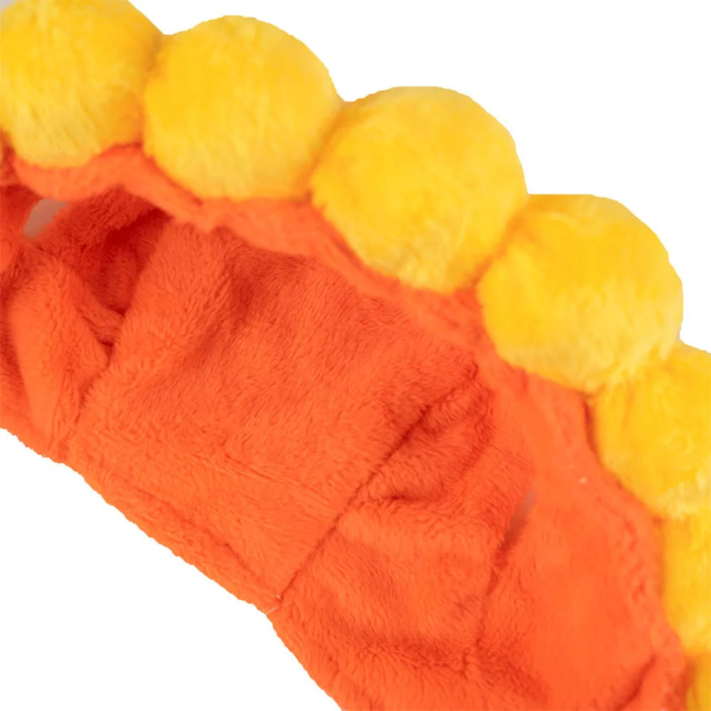 Close-up of a plush hat for pets with orange base and yellow spherical elements on a white background