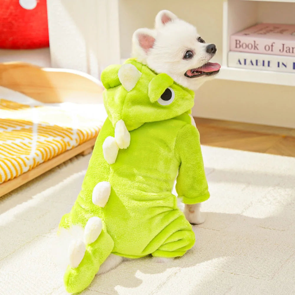 Dog wearing a green dinosaur costume on a bed
