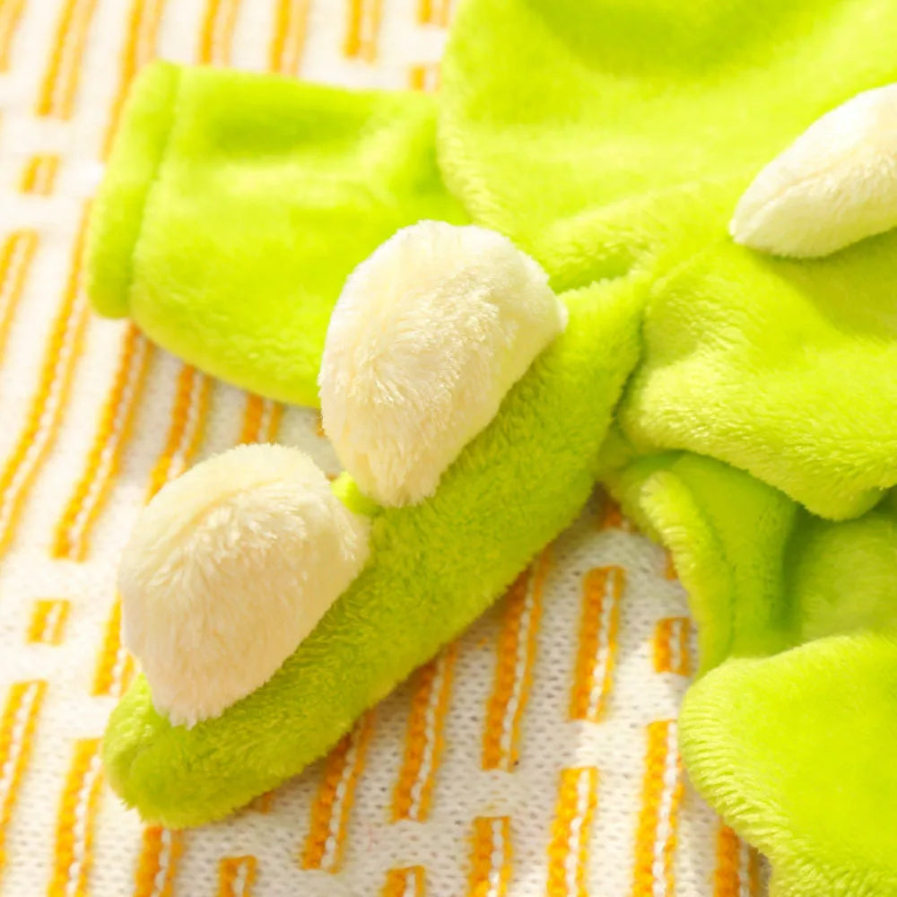 Green plush dog romper resembling a dinosaur on a pattern