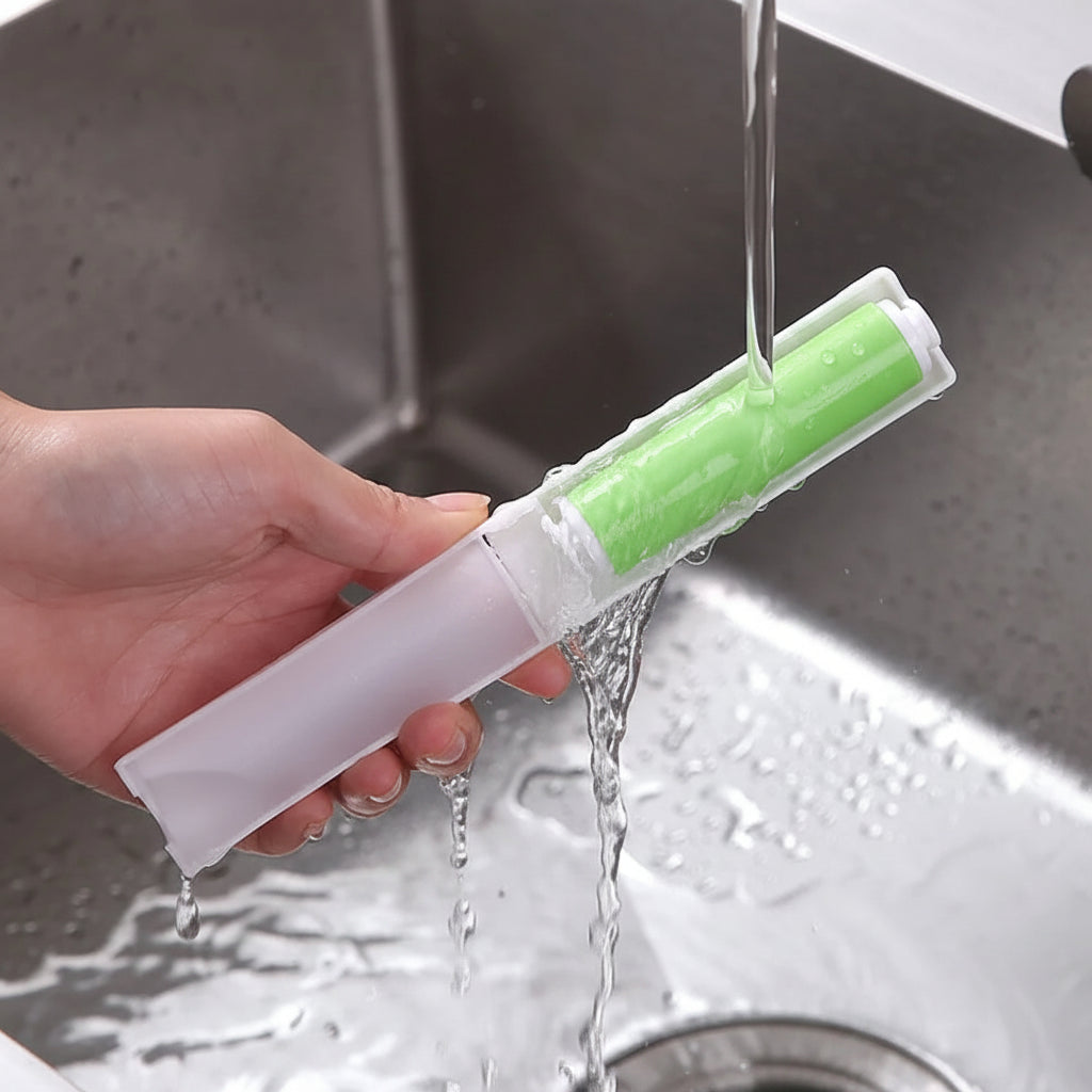 Hand holding a lint roller under running water in a sink