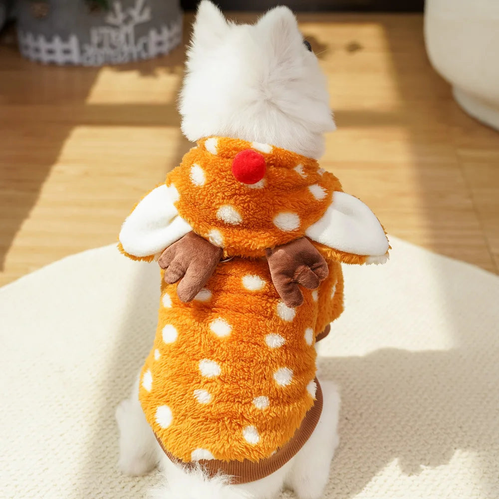 Small dog wearing a deer-themed costume with an orange body and white polka dots on a wooden floor.