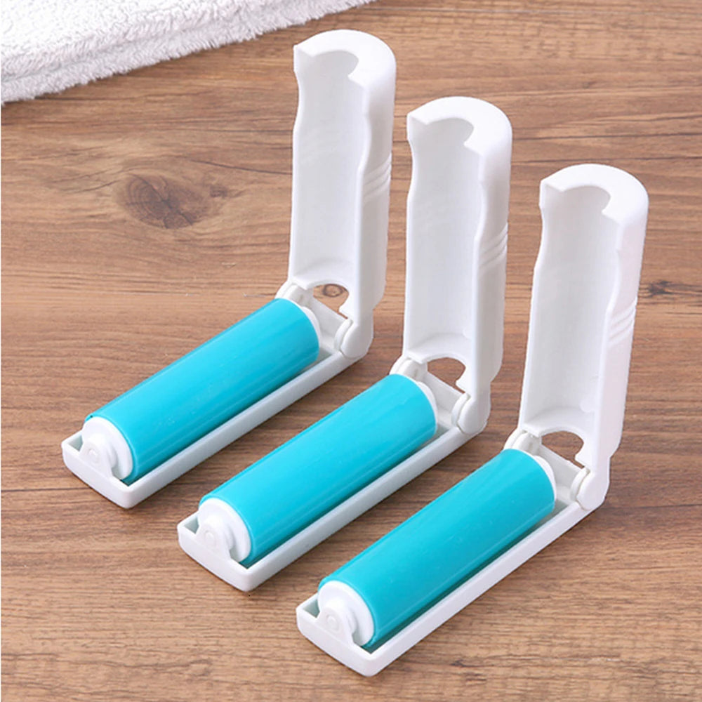 Three lint roller attachments with white plastic handles and bright blue rolling surfaces, arranged on a wooden surface.