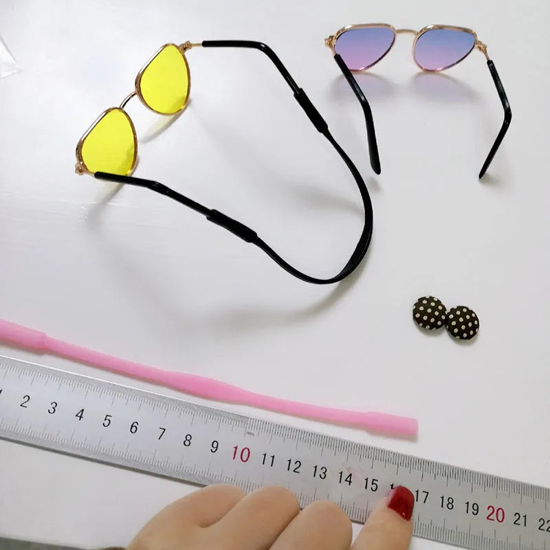 Two pairs of sunglasses, a pink rope to tie around pet's neck, and a ruler for measurement